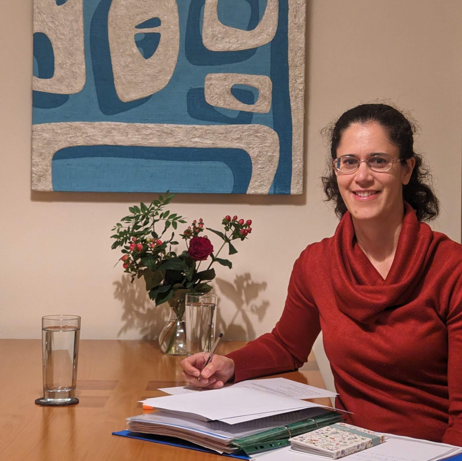 Photo of Aliya Porter Registered Nutritionist ready to do a nutrition consultation, sitting at a table with notes and a glass of water and flowers on the table